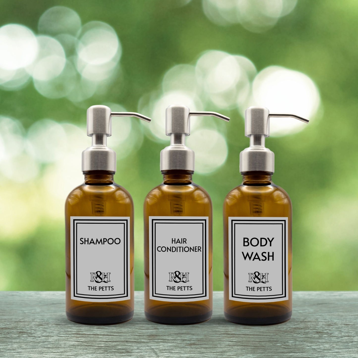 shampoo, hair conditioner and body wash set of three amber glass dispenser bottles for bathroom with custom monogrammed labels and silver pumps