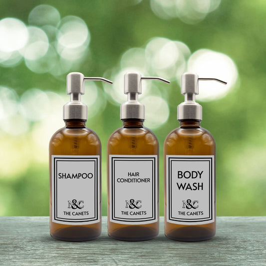 shampoo, hair conditioner and body wash set of three amber glass dispenser bottles for bathroom with custom monogrammed labels and silver pumps